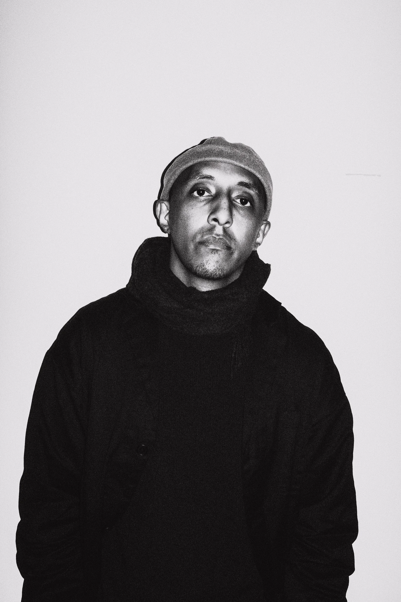 Black-and-white press portrait of Samatar Elmi wearing a cap and dark coat